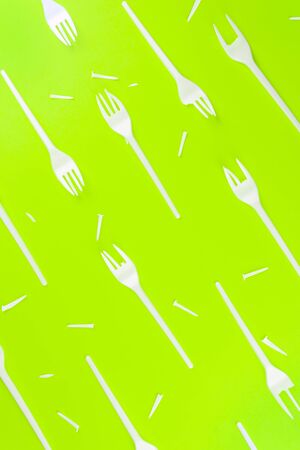 Pattern of a lot of broken plastic forks on a green background. The concept of environmental problems, environmental pollution by plastic waste. Top view.の写真素材