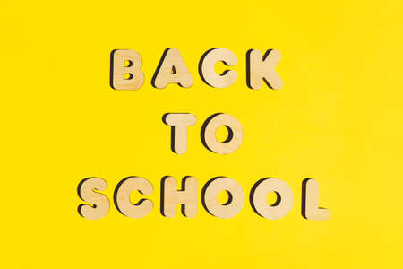 Words Back to School from wooden letters on a yellow background. Back to school concept. Flat lay.