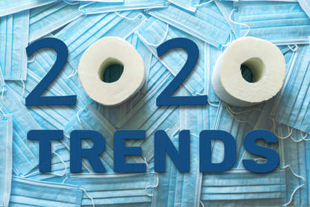 A lot of medical masks and TRENDS 2020 words from blue wooden numbers and letters and toilet paper.