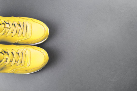 Yellow sneakers on grey background. Concept of sport and healthy lifestyle. Colors of year 2021. Place for text, flat lay, top view.の写真素材