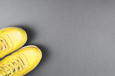Yellow sneakers on grey background. Concept of sport and healthy lifestyle. Colors of year 2021. Place for text, flat lay, top view.の写真素材
