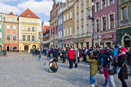 Poznan/Poland - February 6th 2019: Crowd of tourists admiring old town square, taking photos of the little goats (koziolki) high up the cathedral buildingのeditorial素材