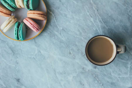 leaves, a cup of coffee and pastel French macarons cakes on a marble surface. Flat lay composition from above, top view . background with copy space for text from right.の写真素材