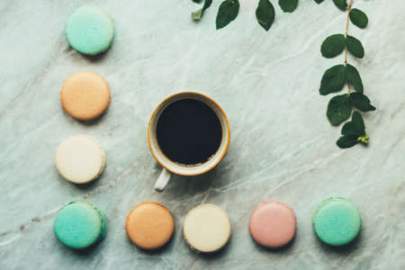 leaves, a cup of coffee and pastel French macarons cakes on a marble surface. Flat lay composition from above, top view . background with copy space for text from right.の写真素材