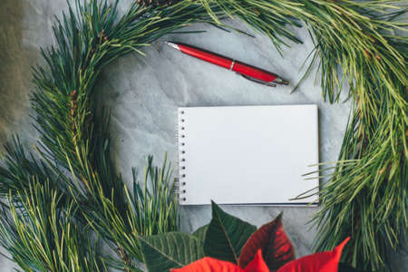 Christmas closeup mockup with poinsettia, pine wreath, notebook, with copy place.