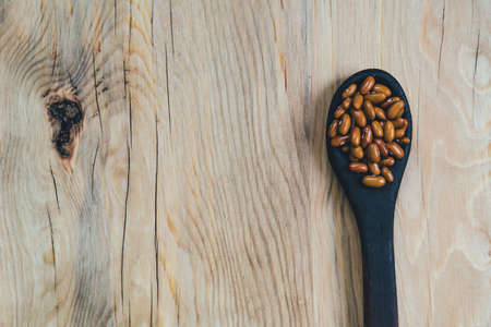 Brown beans in a spoon on a wooden backgroundの写真素材
