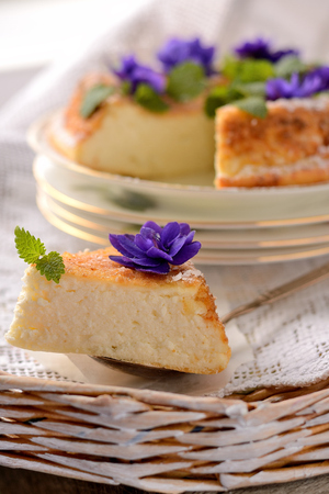 Casserole of cottage cheese with violets on wooden tableの写真素材