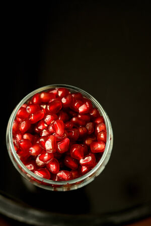 pomegranate seeds in a glass on a blackの写真素材