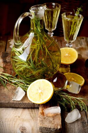 Green estragon lemonade pitcher with two glasses on a wooden table in the sun の写真素材