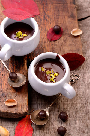 flavored hot chocolate in small ceramic chashkahna wooden table with red fallen autumn leaves and vintage teaspoons. Selective focusの写真素材