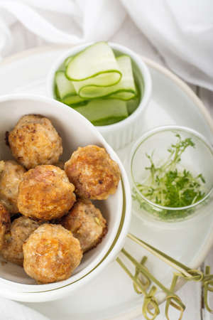 Minced meat balls with cucumber cress in a white bowl on a white background with a tablecloth  . Selective focusの写真素材