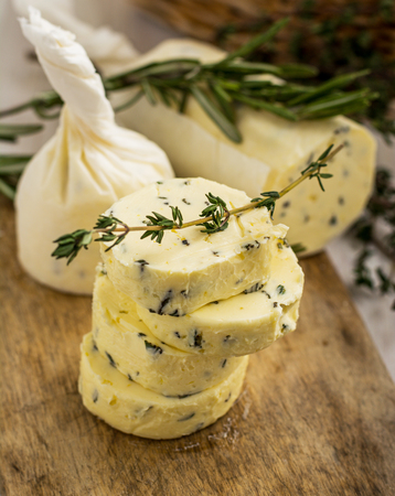 Butter with thyme and rosemary and lemon zest. Sliced on a wooden board with herbs. selective Focusの写真素材