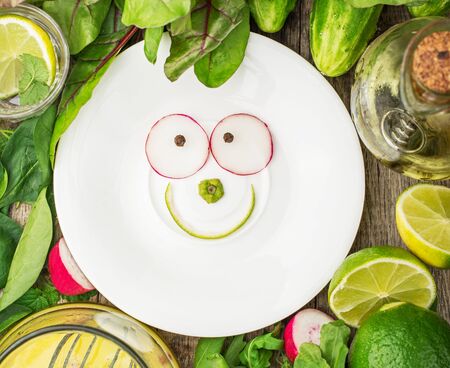 White plate with a smile of spring ingredients surrounded by spring salads and vegetables. Concept of healthy food. selective Focusの写真素材