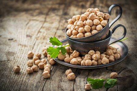 Vintage silver cup with Dry raw organic chickpeas,  cilantro  on old wooden table. Selective focusの写真素材