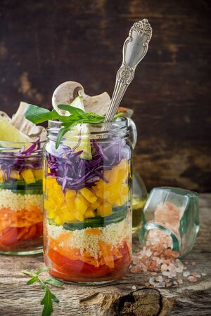 Bright rainbow salad  of tomatoes, carrots, pepper, red cabbage, arugula and mushrooms with butter and sea salt on a pink background vegetables and herbs. Trends in healthy eating. Selective focus.の写真素材