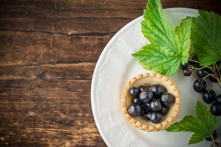 Delicious crispy tarts with black currants on wooden table, closeupの写真素材