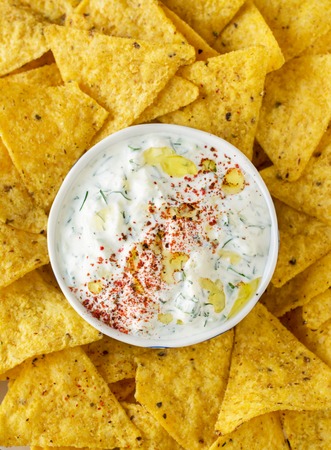 Tortilla chips and cream sauce with fresh herbs and garlic in a ceramic bowl. selective Focus