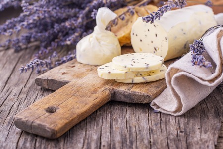 Butter with dried lavender flowers wrapped in parchment on a wooden cutting board. The concept of healthy homemade natural nutrition. selective Focusの写真素材