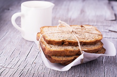 Slices of homemade dark fragrant fresh bread with poppy seeds, flax, sunflower and pumpkin on dark...