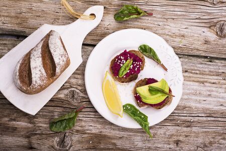 Sandwiches for breakfast or snack of hummus with roasted beets and chickpeas with avocado, lemon juice, juicy fresh chard and grain bread and white sesame seeds. The concept of healthy natural foods.の写真素材