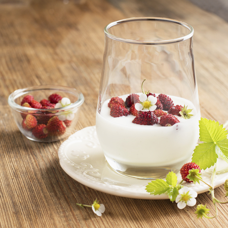Natural yogurt with fresh strawberries for breakfast served in portions in a glass on a wooden background. The concept of a healthy natural food. selective focusの写真素材