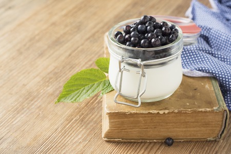 Portion breakfast in a glass jar with yogurt and fresh ripe blueberries on a wooden background.の写真素材