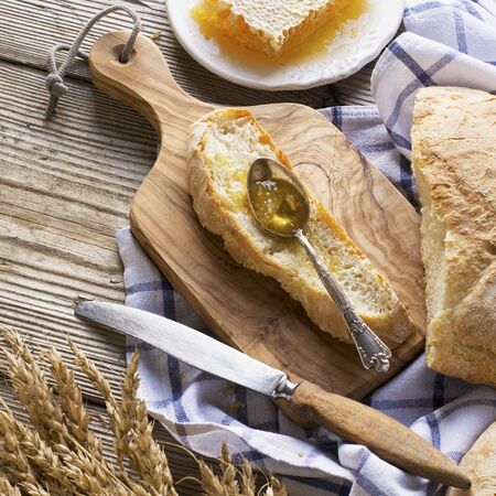Golden fragrant twisted baguettes on a simple wooden background on a white towel in hlopkovoi blue...