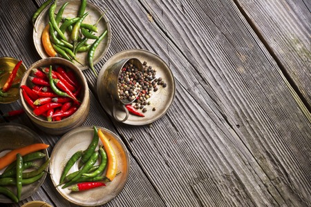 Coloured bright hot peppers, bell pepper, chili powder in a metal vintage cups and saucers on a dark wooden background. selective focusの写真素材