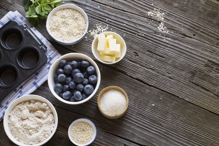 Ingredients for blueberry muffins on a dark wooden background flour, sugar, butter, blueberry, blueberries, oatmealの写真素材