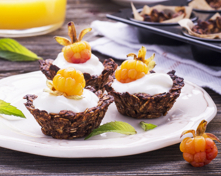 Healthy breakfast. Homemade granola cup with yogurt and fresh cloudberries on a simple wooden background on a ceramic plate. selective focusの写真素材