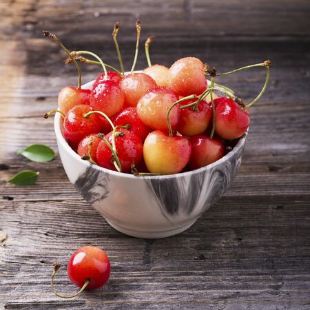 Ripe yellow cherries in a gray marble bowl on a wooden background. selective focusの写真素材