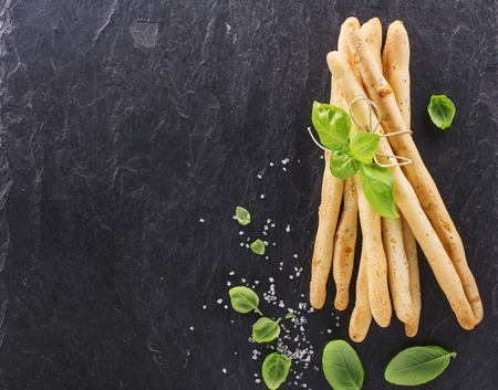 Fresh homemade crispy bread sticks with thyme and sea salt on a black background with fresh herbs. selective focusの写真素材