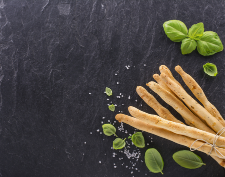 Fresh homemade crispy bread sticks with thyme and sea salt on a black background with fresh herbs. selective focusの写真素材