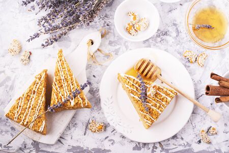 Fragrant homemade honey cake cake with nuts and honey lavender on gray concrete background with nuts and fresh honey in the horizontal version. lavender decorated. selective focusの写真素材