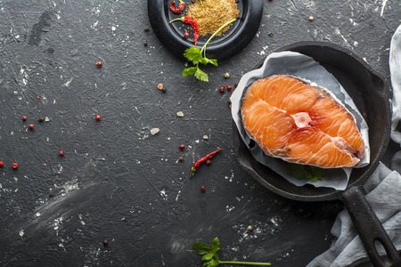 Portion magnificent sea wild northern salmon before cooking with spices and salt on a dark background in the form of cast iron.の写真素材