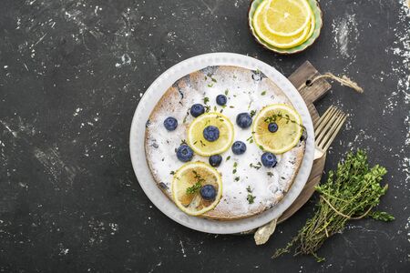 Comfort food. Homemade flavored sponge cake with blueberries and slices of lemon on a marble background. Topの写真素材