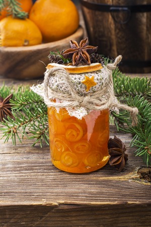 Homemade jam handmade orange peel in the form of snails in a small glass jar as  gift for the new year on  wooden background with fir branches and oranges in the . selective focusの写真素材
