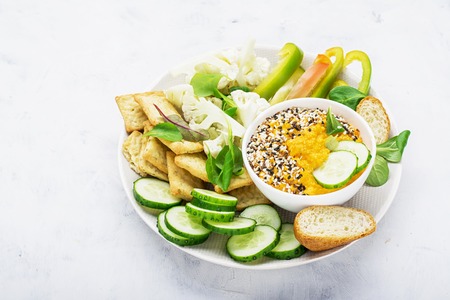 Vegetables bowl of sauce: carrot dip with slices of crispy bread, cucumber, sweet peppers,...