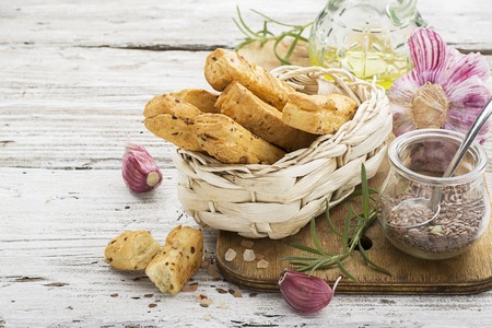 Bread sticks from puff pastry with flax and sesame seeds on a light background with rosemary.