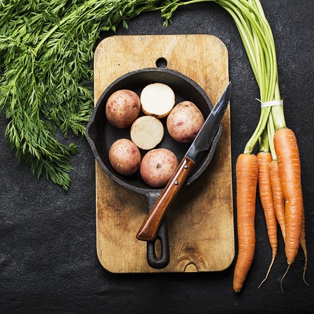 Fresh organic farm vegetables: carrots, potatoes, fresh herbs, spices and oil on a dark textured...