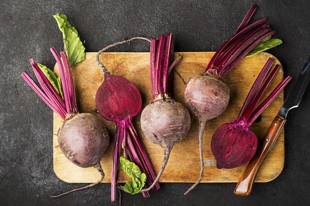 Raw organic farm beetroot on a vintage wooden cutting board on a plain black background. Top View.の写真素材