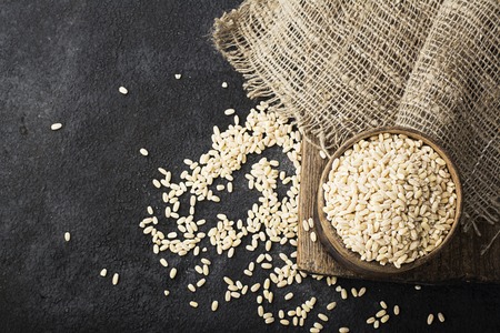 Pearl dry cereal in a vintage wooden bowl on a plain dark background for text placement and advertising. Selective focus.の写真素材