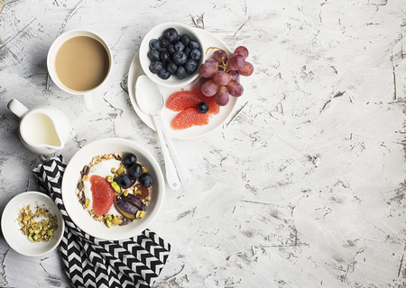 Seasonal healthy breakfast: yoghurt, chocolate granola, pink grapefruit, grapes, pistachios. Top view. Copy space. flat layの写真素材
