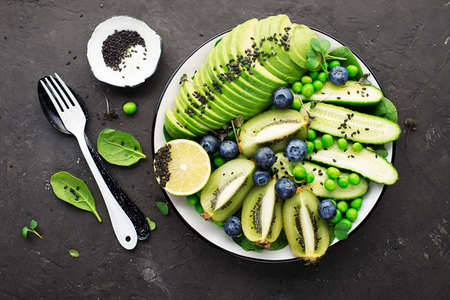 Green fruit vegetables summer detox bowl of salad. Avocado, spinach, cucumber, micro greens,...