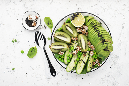 Green fruit vegetables summer detox bowl of salad. Avocado, spinach, cucumber, micro greens, blueberries one plate dish. Top Viewの写真素材