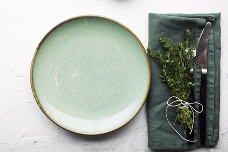 Table gentle simple serving in shades of green with a bunch of thyme on a light background. Top view.の写真素材