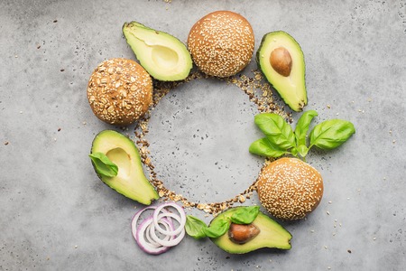 Ingredients for making healthy vegetarian avocado burger with basil, red onion, avocado on cereal...