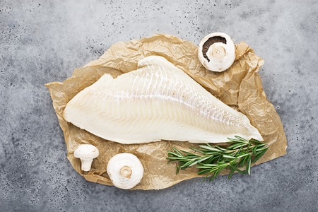 Fillet of sea white cod fish on parchment with fresh raw champignons before cooking. Zero waste kitchen. Healthy food seafood. Top view, spaceの写真素材