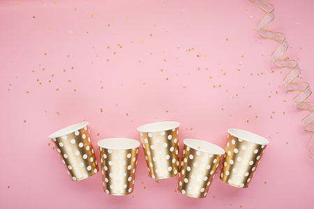 Universal trendy festive background pink gold with confetti, paper fashion cups on a delicate pink background. Concept for any fun bright project. Horizontal, copy spaceの写真素材