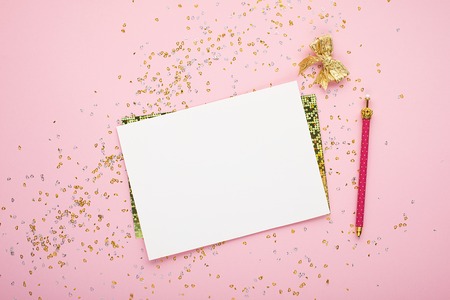 Blank sheet of paper, notebook on a festive pink background with golden confetti and glitter. Universal background for a project of a birthday party, wedding. Flay lay, copy space,の写真素材